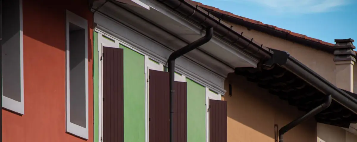 Facciate colorate di case in un centro storico friulano, con scuri in legno e grondaie